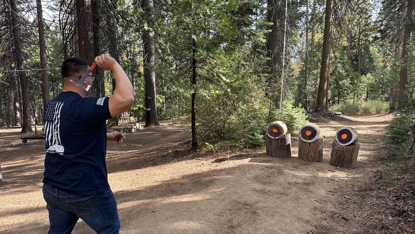 Men from New Hope throwing axes at the annual Man Camp in the forest