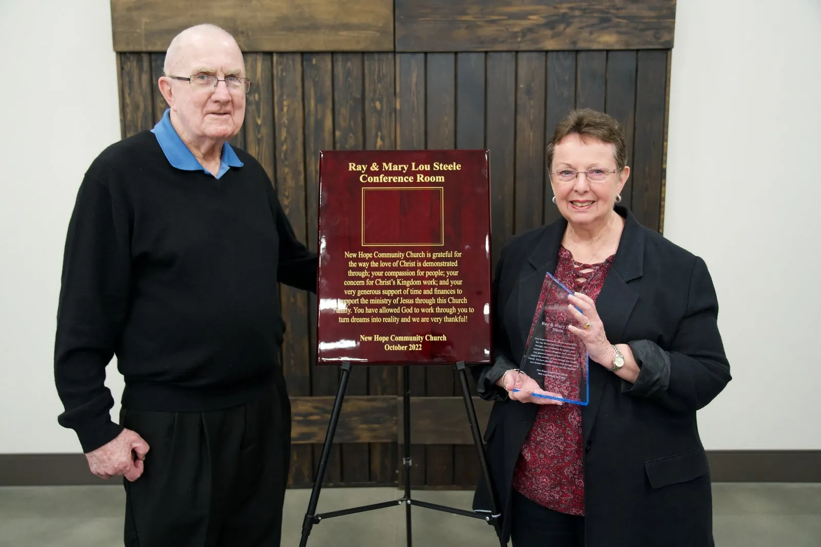 Ray and Mary Lou Steele standing beside the dedication plaque for the Ray and Mary Lou Steele Conference Room at New Hope