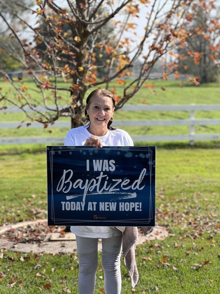 A New Hope member holding an I was baptized today at New Hope sign on the church lawn