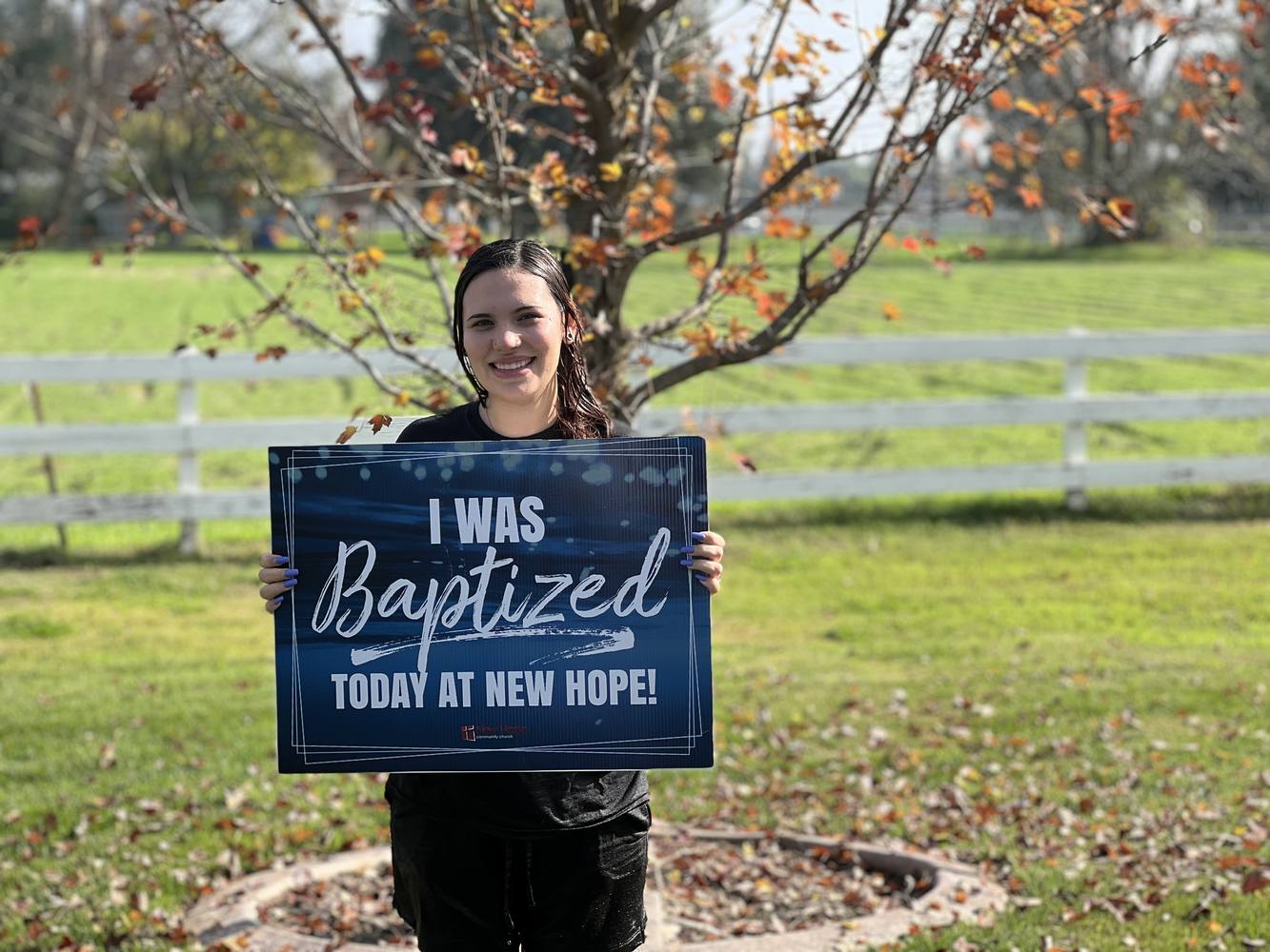 A young New Hope member holding an I was baptized today at New Hope sign on the church lawn