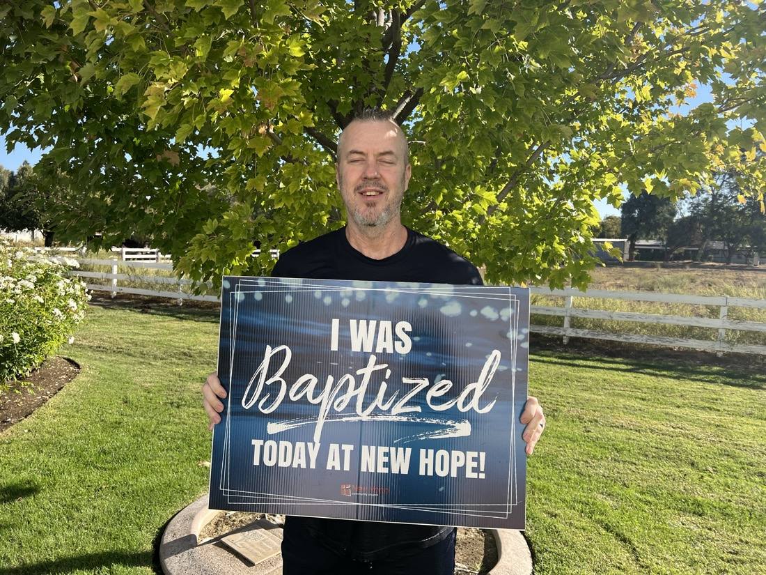 A New Hope member holding an I was baptized today at New Hope sign