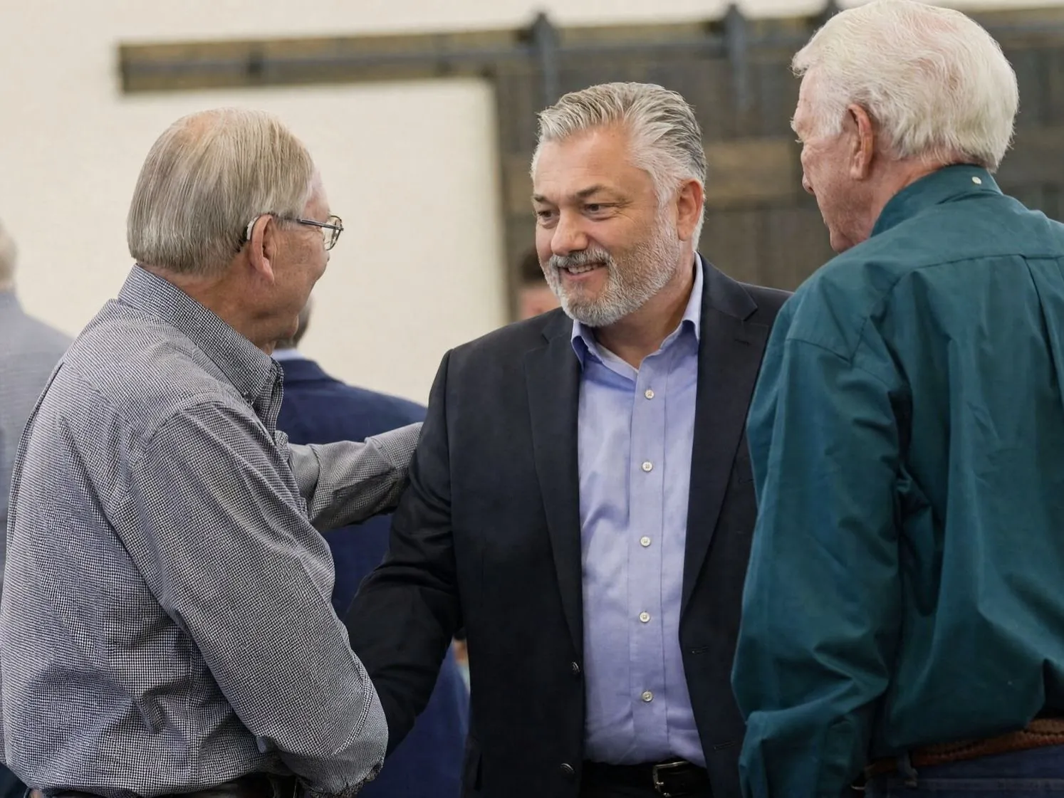 Pastor Mark Addis talking with two men in the Barn after a service