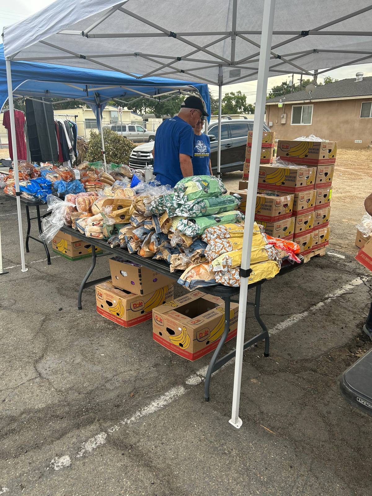 A long table covered with bagged bread and fresh produce, with boxes stacked underneath