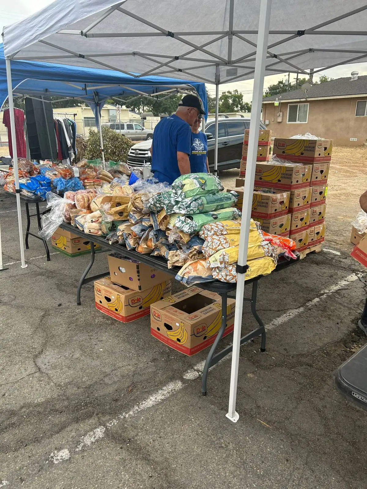 A long table covered with bagged bread and fresh produce, with boxes stacked underneath