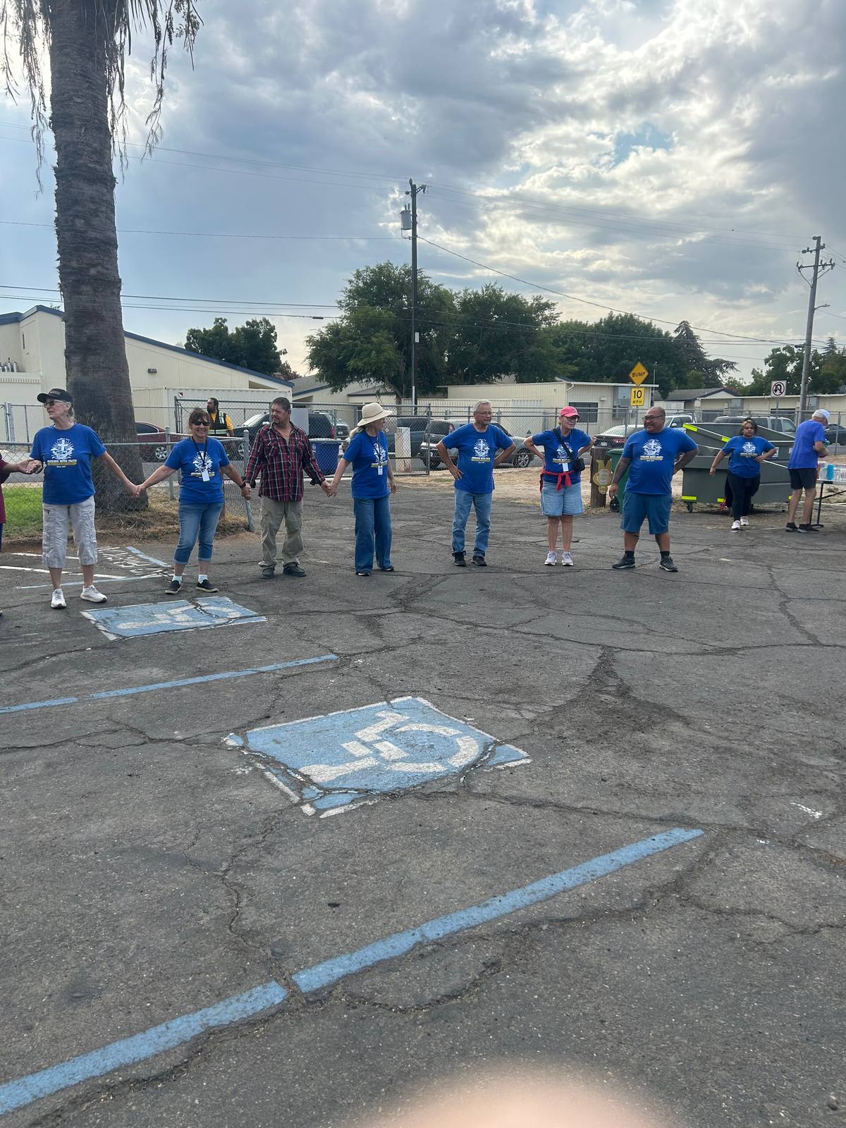 Volunteers standing in a wide circle holding hands in the parking lot before the morning starts