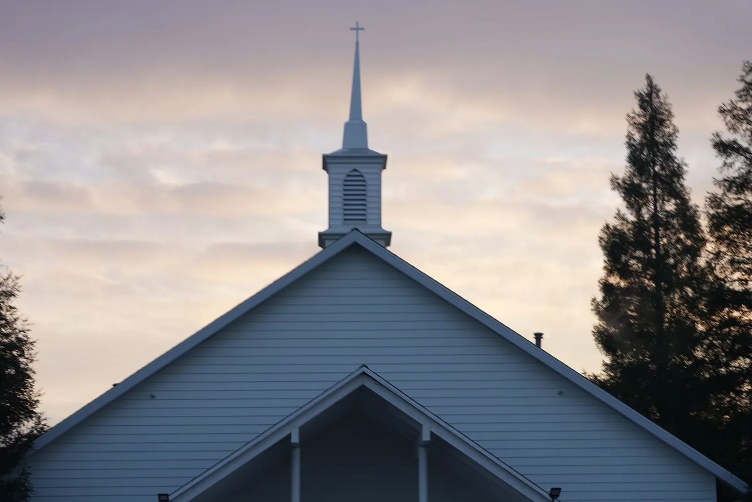 The New Hope steeple and cross against a pale dawn sky in Clovis