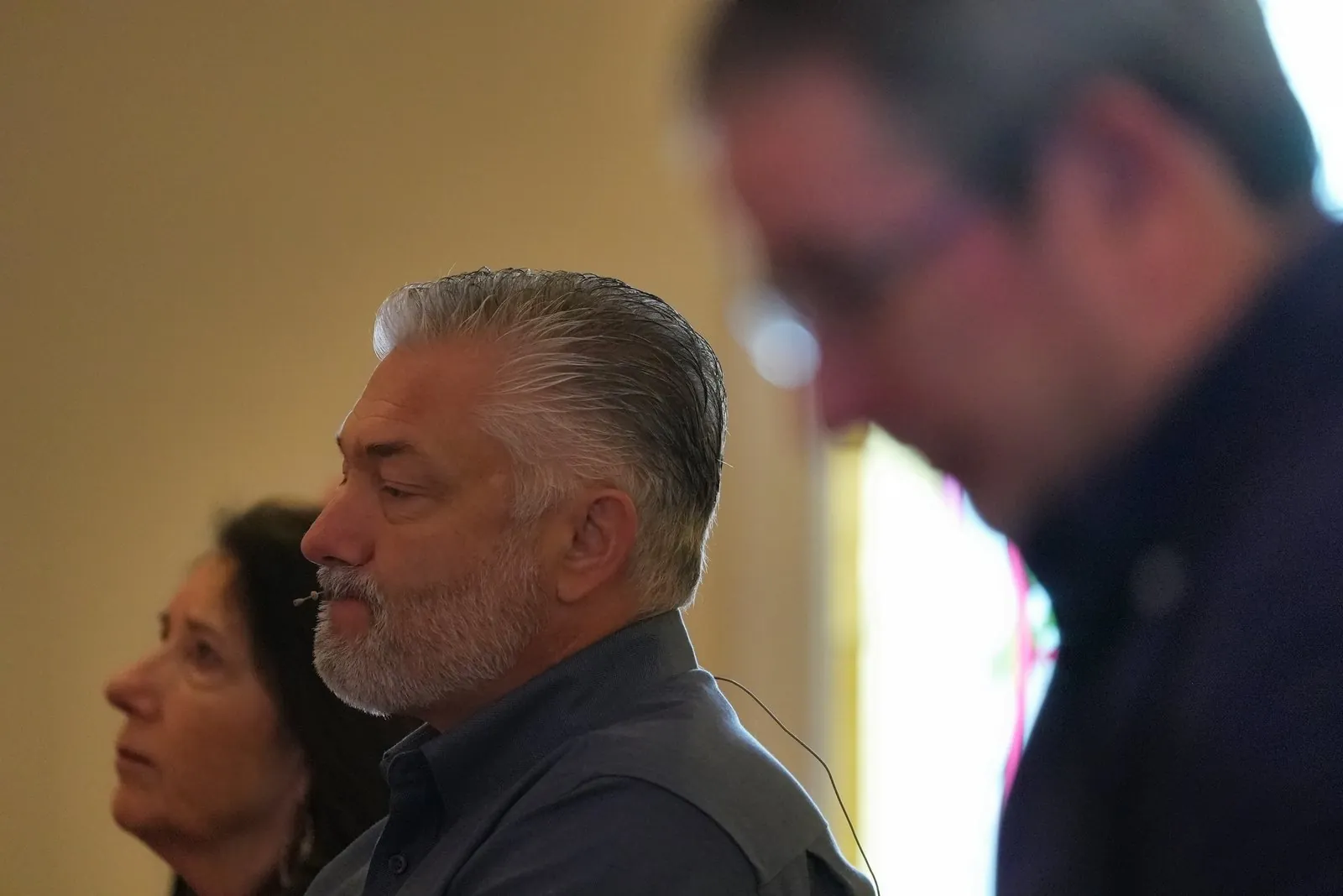 Pastor Tim Rolen wearing a headset microphone, with Pastor Mark Addis in the foreground, both in profile, during a Sunday service