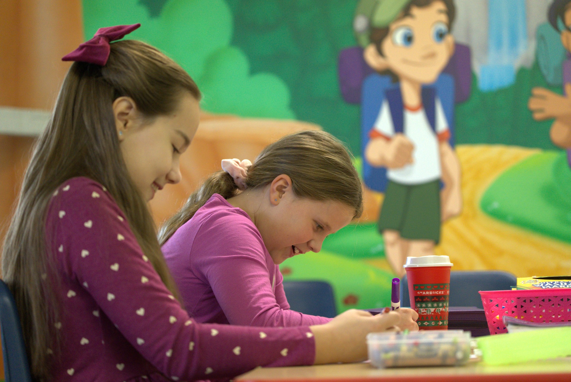 A New Hope Kids volunteer leaning in at the craft table with two children working on a coloring project
