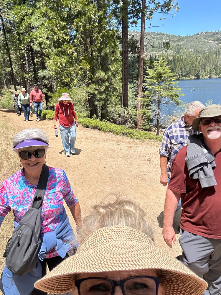 A group of Ignite couples walking on a dirt trail around Hume Lake, the lake visible through the pines