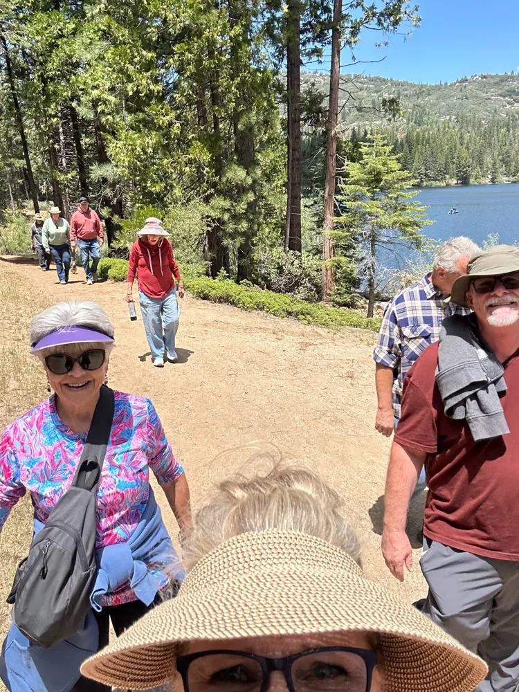 A group of Ignite couples walking on a dirt trail around Hume Lake, the lake visible through the pines