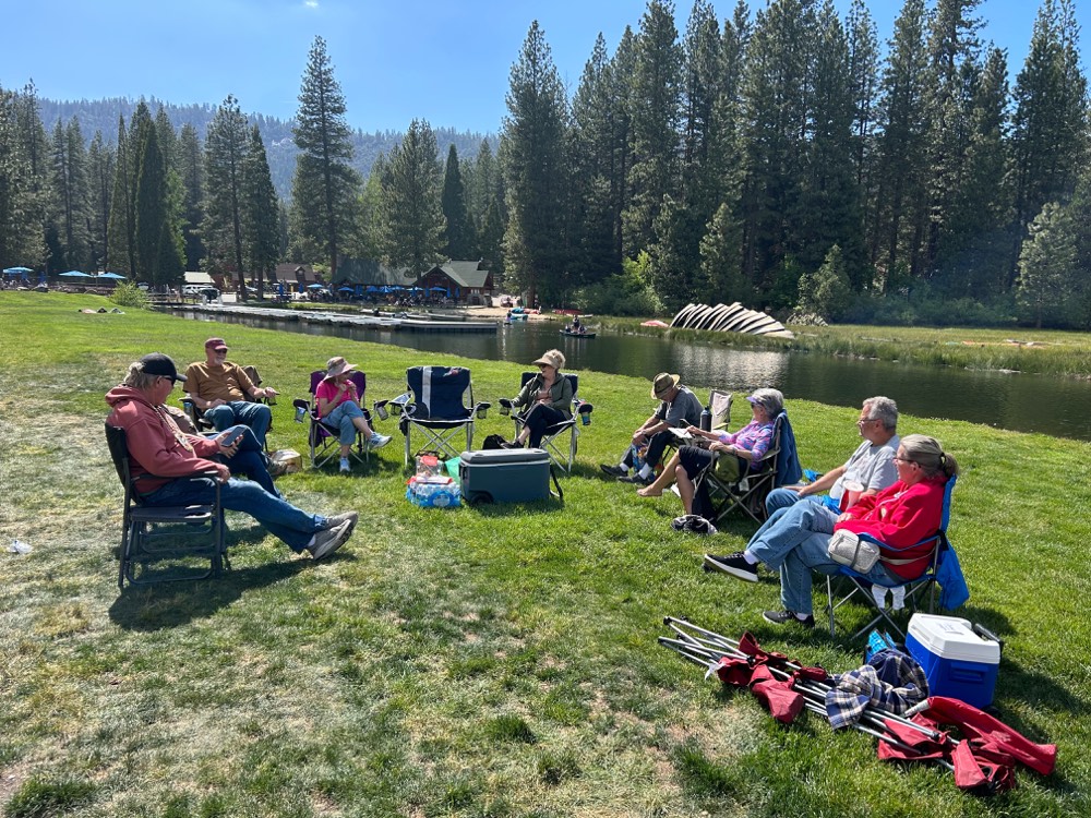 A circle of Ignite couples in lawn chairs talking by the Hume Lake waterfront