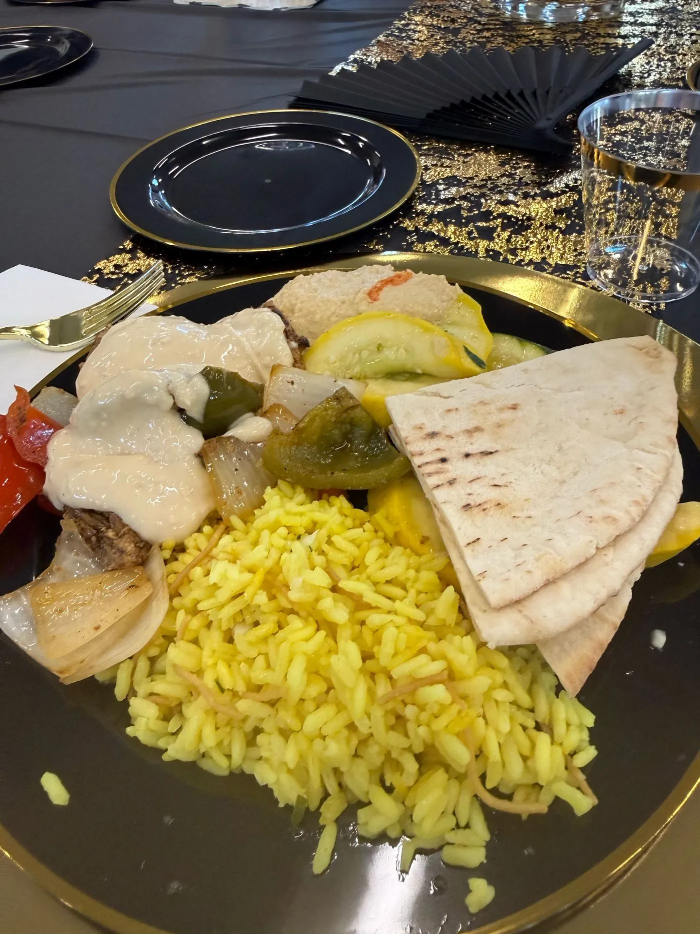 A dinner plate with grilled chicken, rice, pita, and roasted vegetables