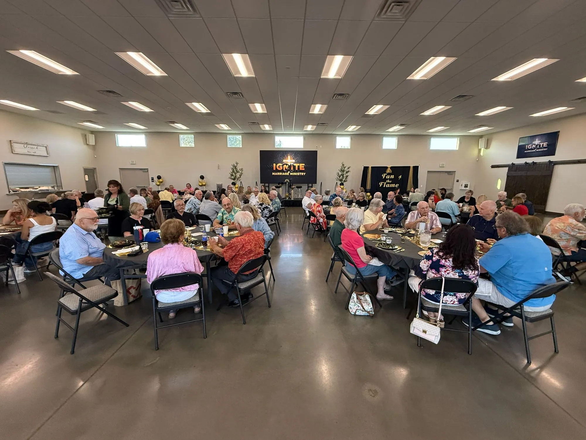 Couples at round tables set with black and gold decor, talking over dinner