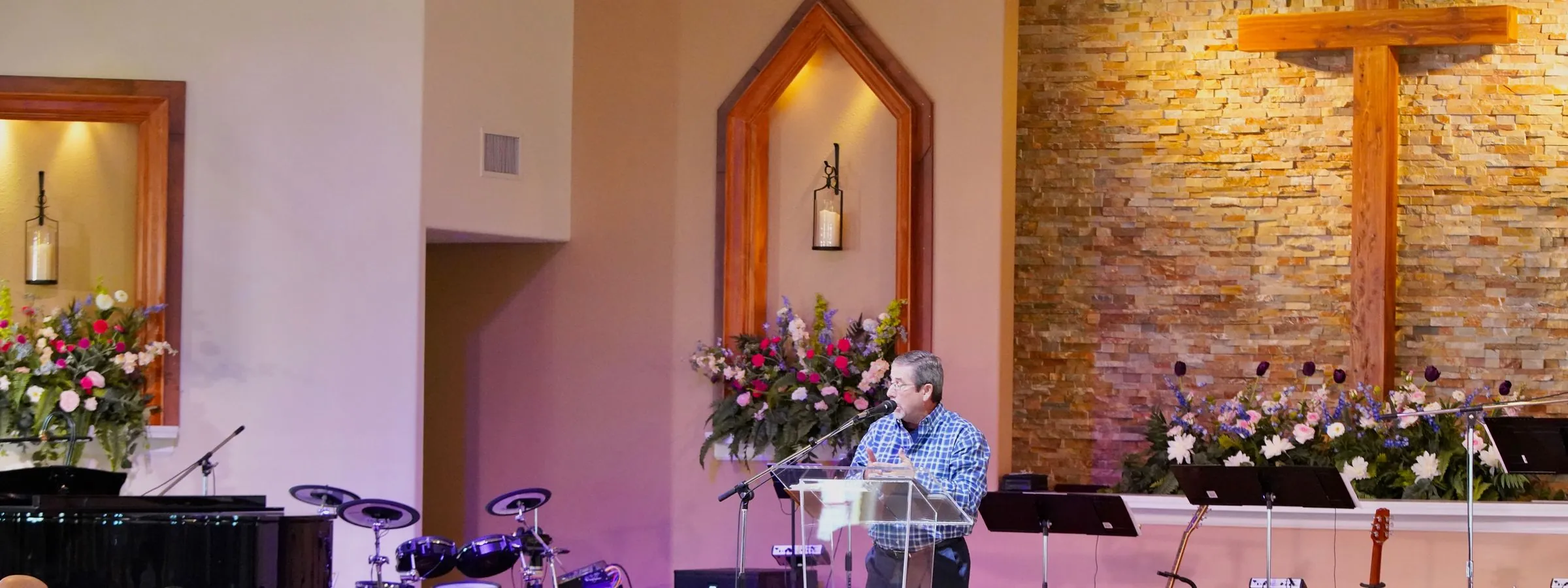 The New Hope sanctuary stage with the wooden cross and fresh flowers, cleared and quiet