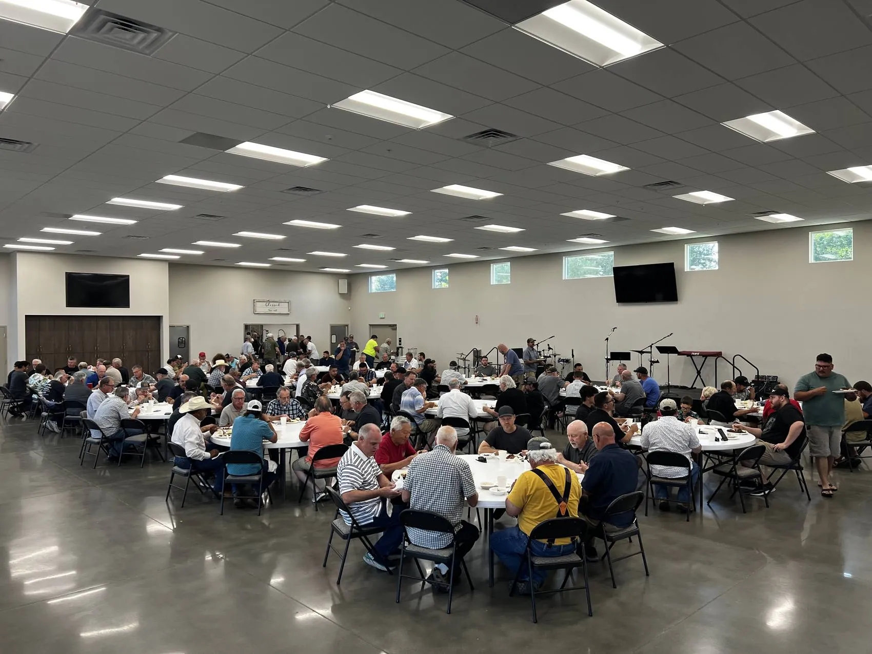 A hall full of men of New Hope seated at tables together
