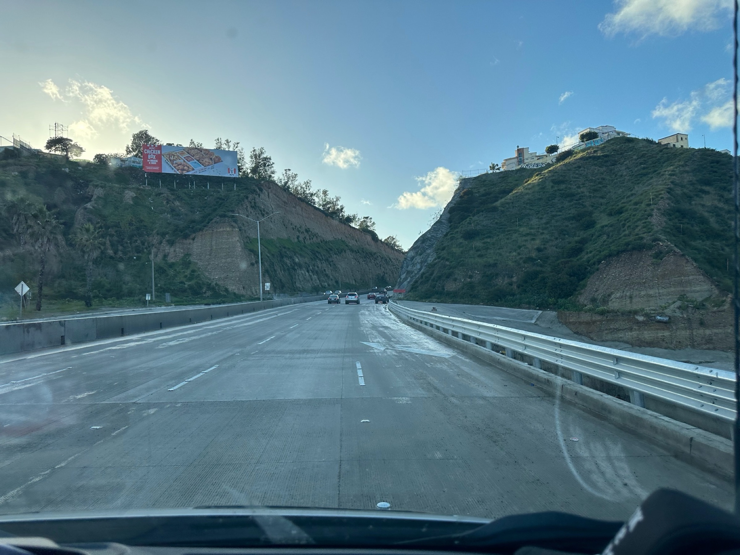 A view down a Baja California highway from inside the team van, hillside homes on either side