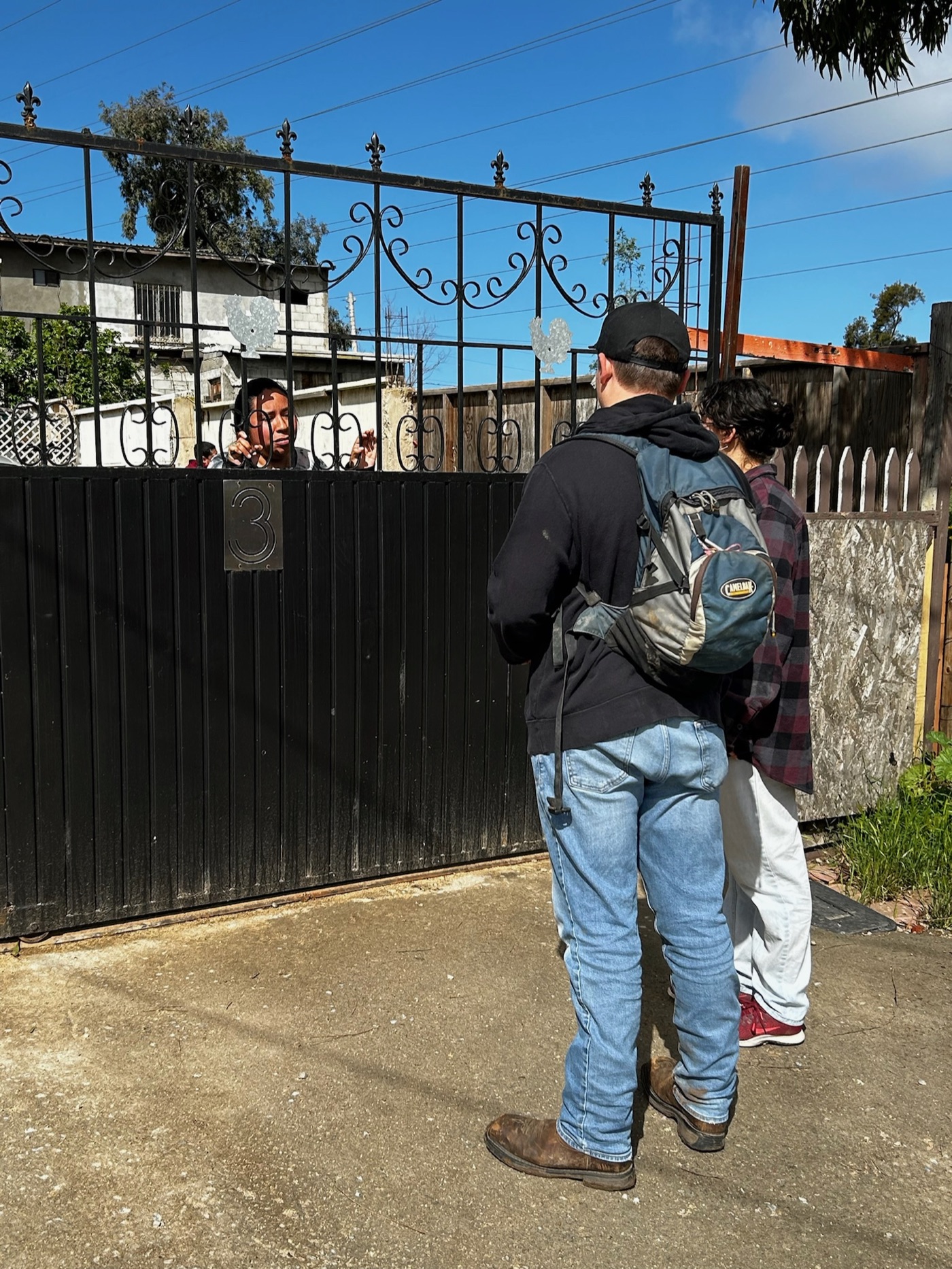 A New Hope team member talking with a Mexican girl through a gate, a relational moment outside a Rosarito home