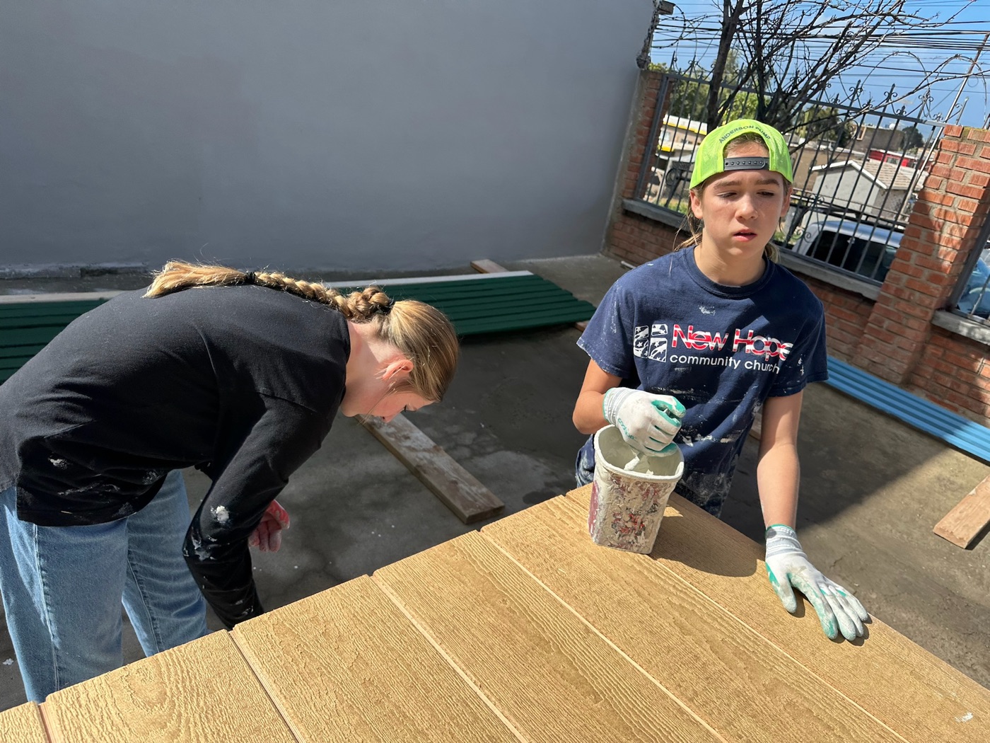 New Hope team members staining wood paneling at the Mexico build site