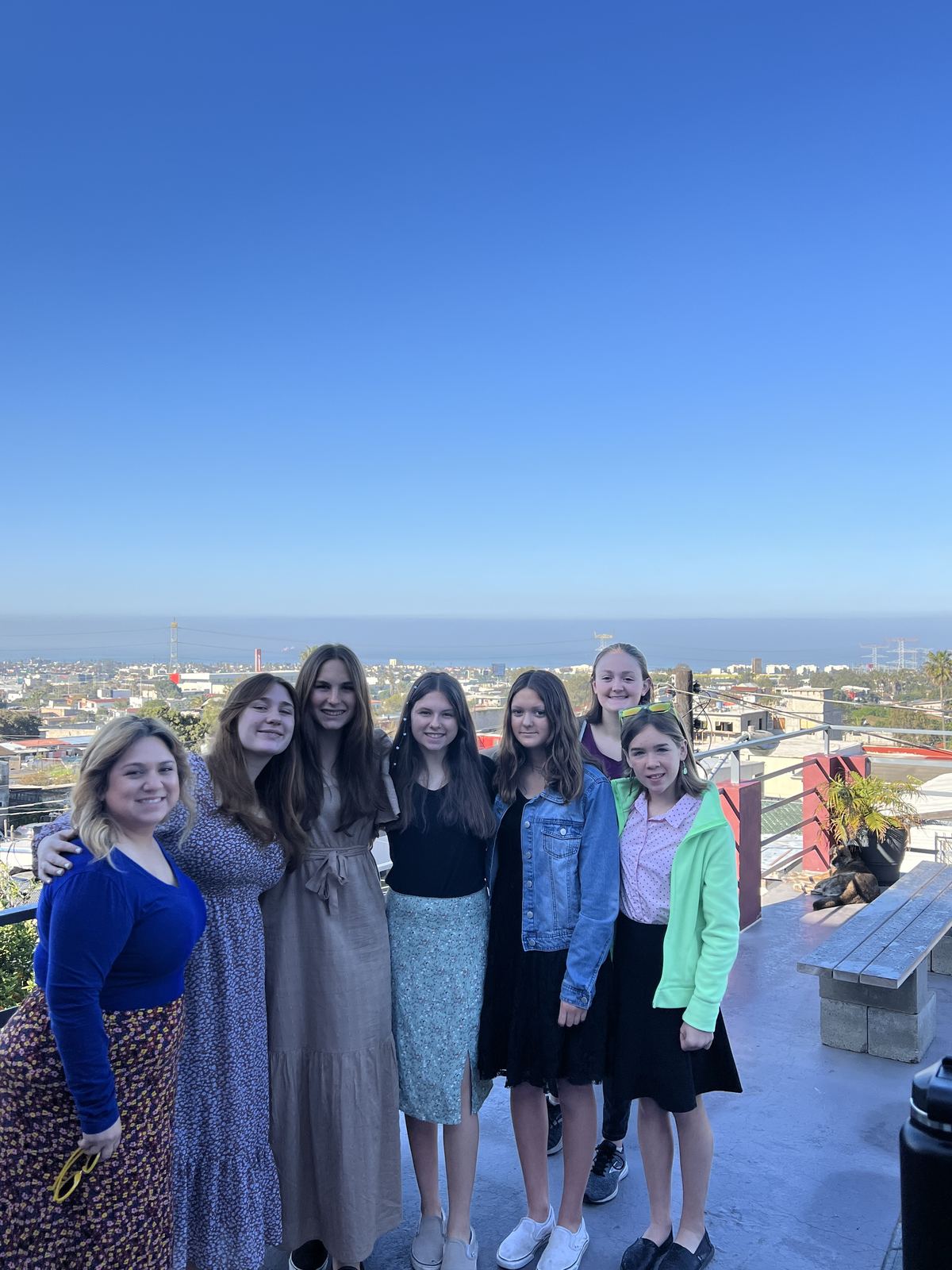 Students from the New Hope team standing together on a terrace above Rosarito, the town and the ocean behind them