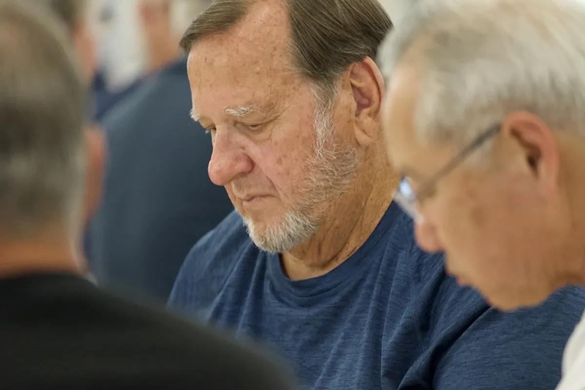 Two New Hope men with heads bowed in a moment of reflection during a teaching event
