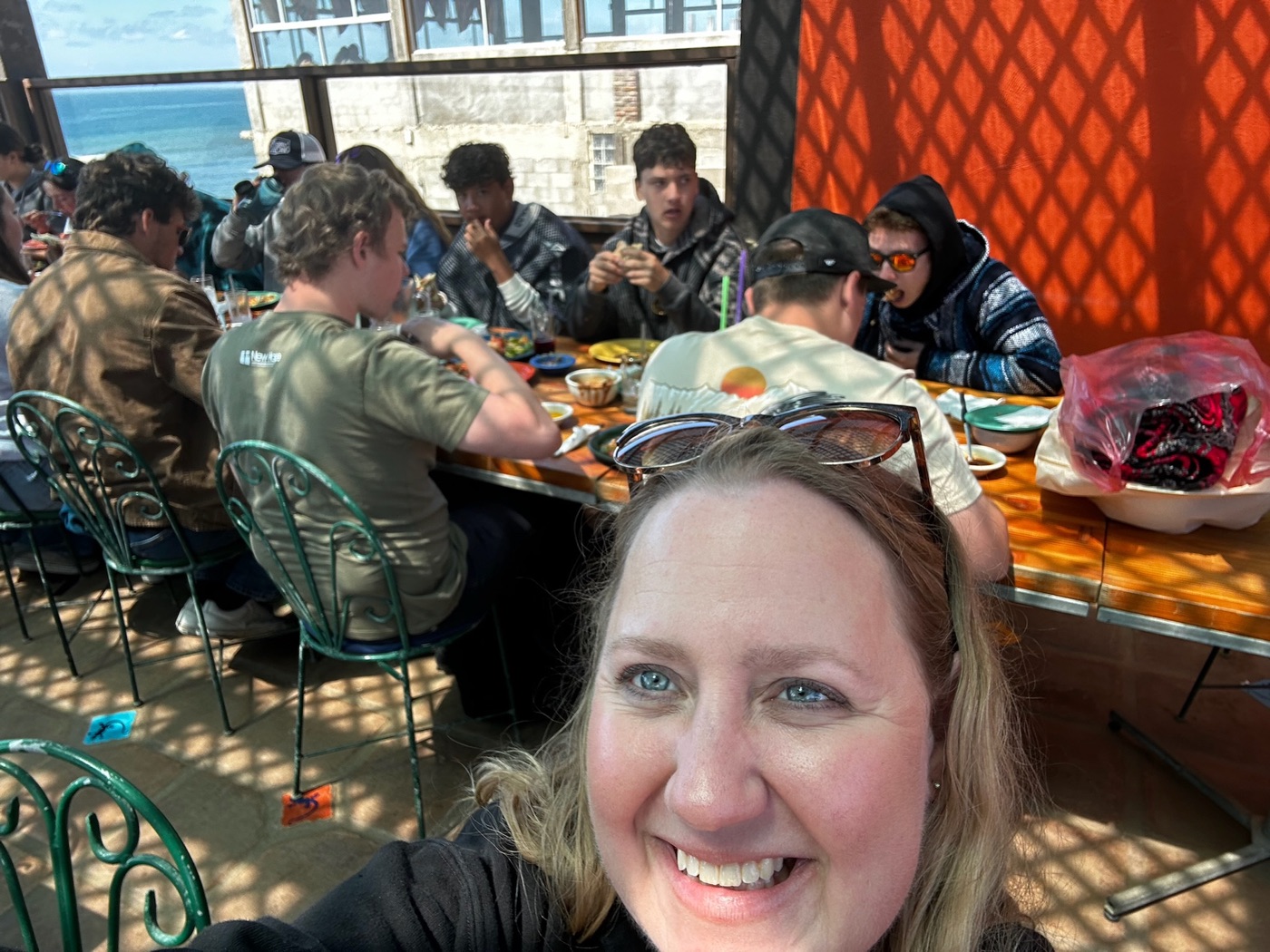 New Hope Mexico trip team sharing a meal at long outdoor tables overlooking the ocean in Rosarito