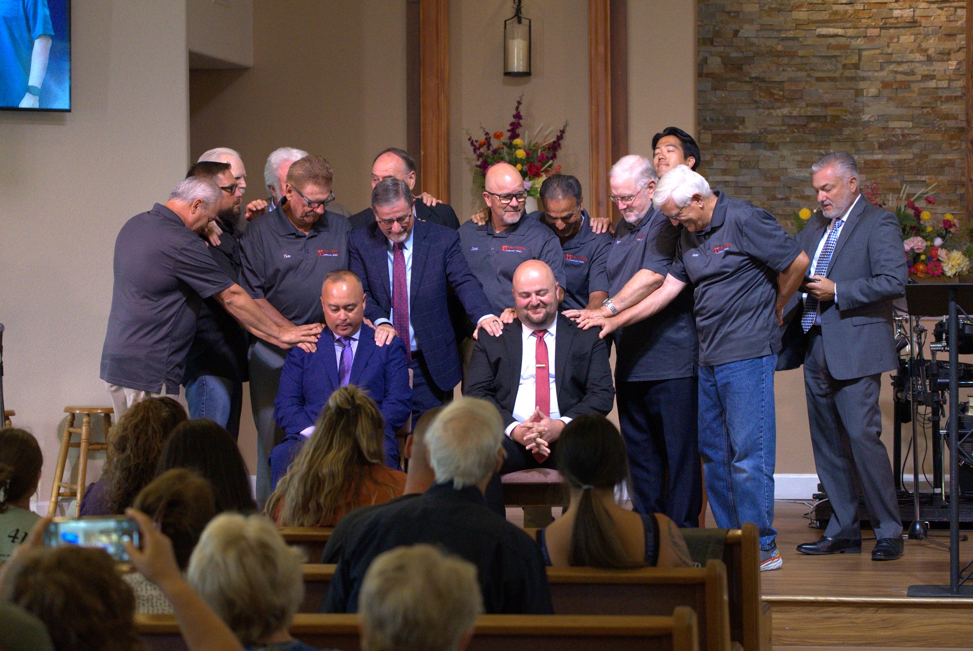 New Hope elders praying over two men at the front of the sanctuary