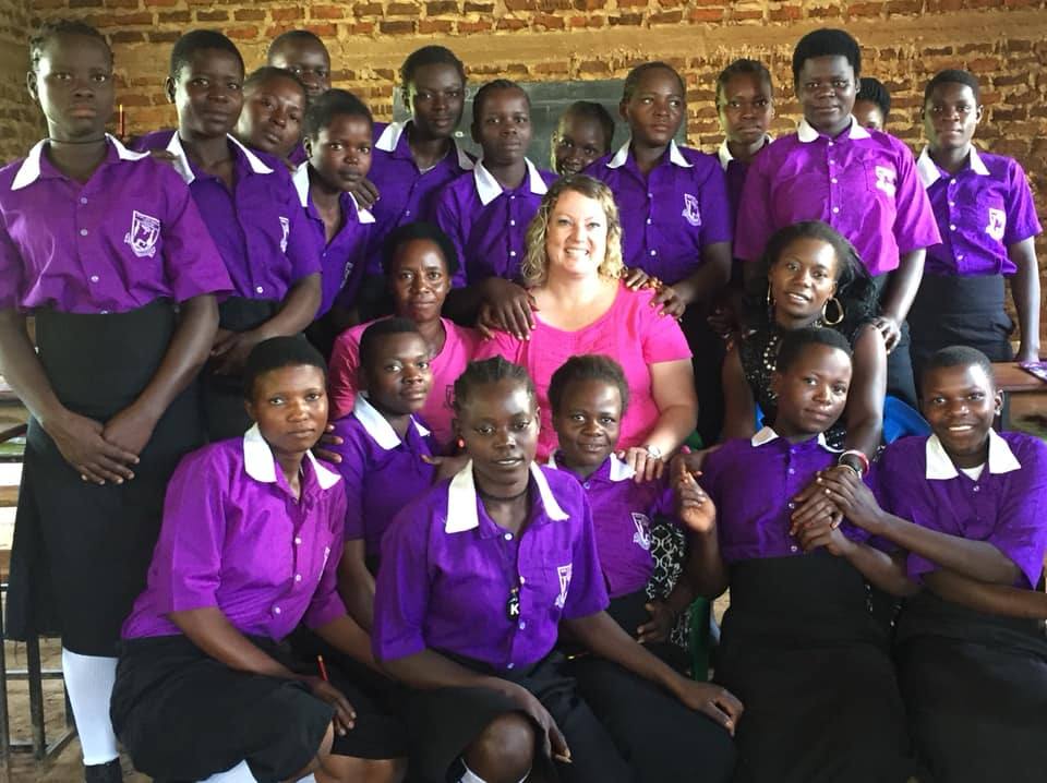 A New Hope team member surrounded by students in purple uniforms at a partner school in Africa