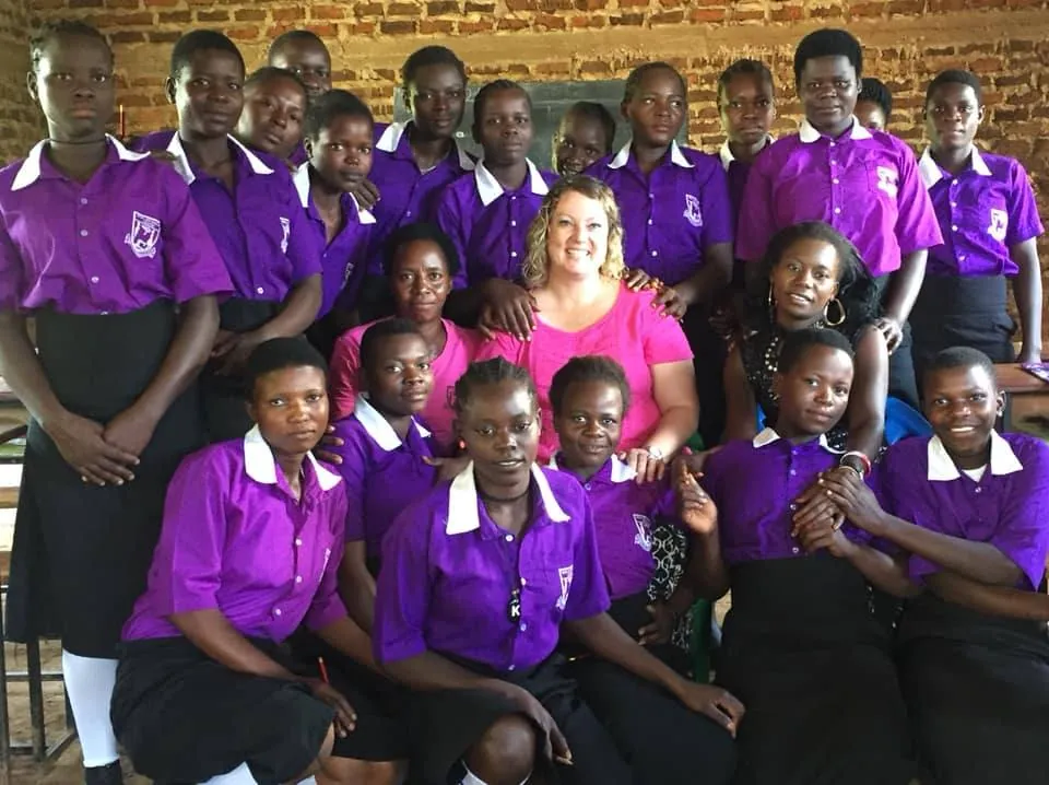 A New Hope team member surrounded by students in purple uniforms at a partner school in Africa