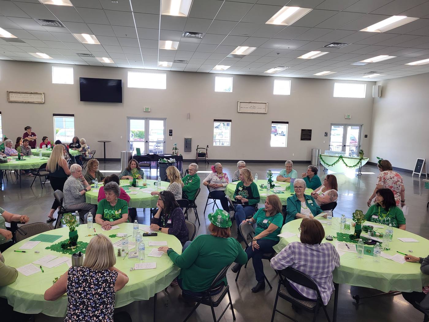 Women of many ages seated around green-decorated tables at a New Hope women's ministry gathering