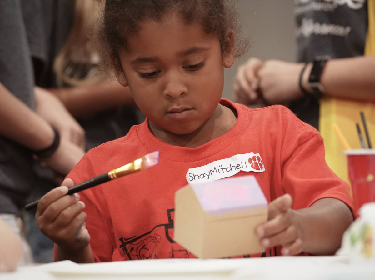 A child wearing a check-in name tag working on a craft at VBS at New Hope in Clovis