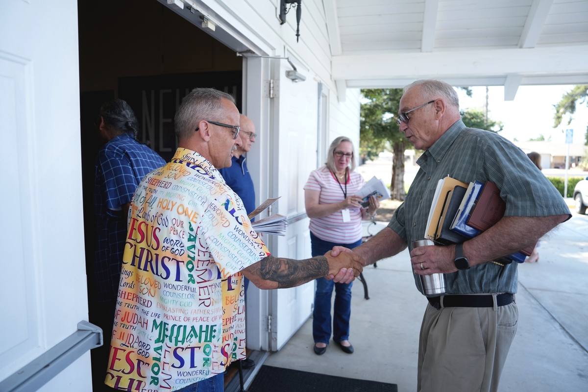 Two men shaking hands at the sanctuary doors before a Sunday service at New Hope in Clovis