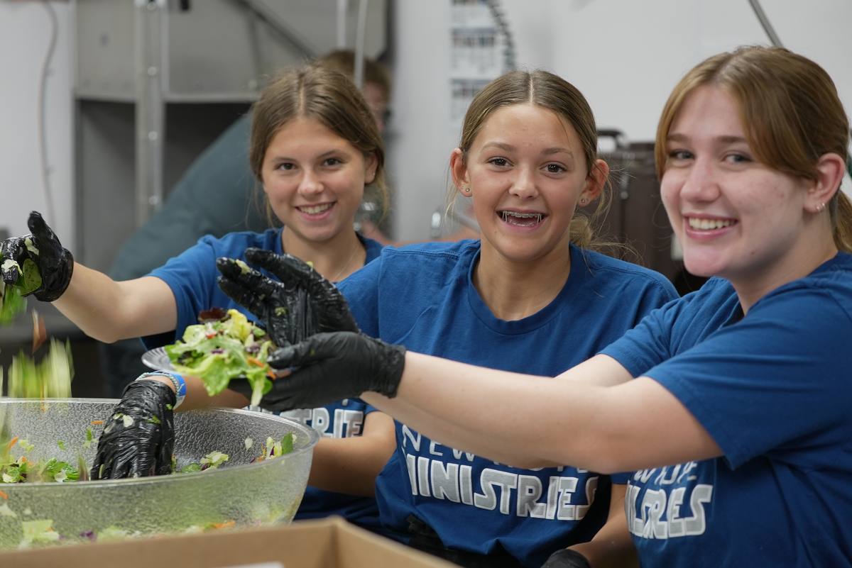 Students serving food down a serving line at a New Hope gathering in Clovis