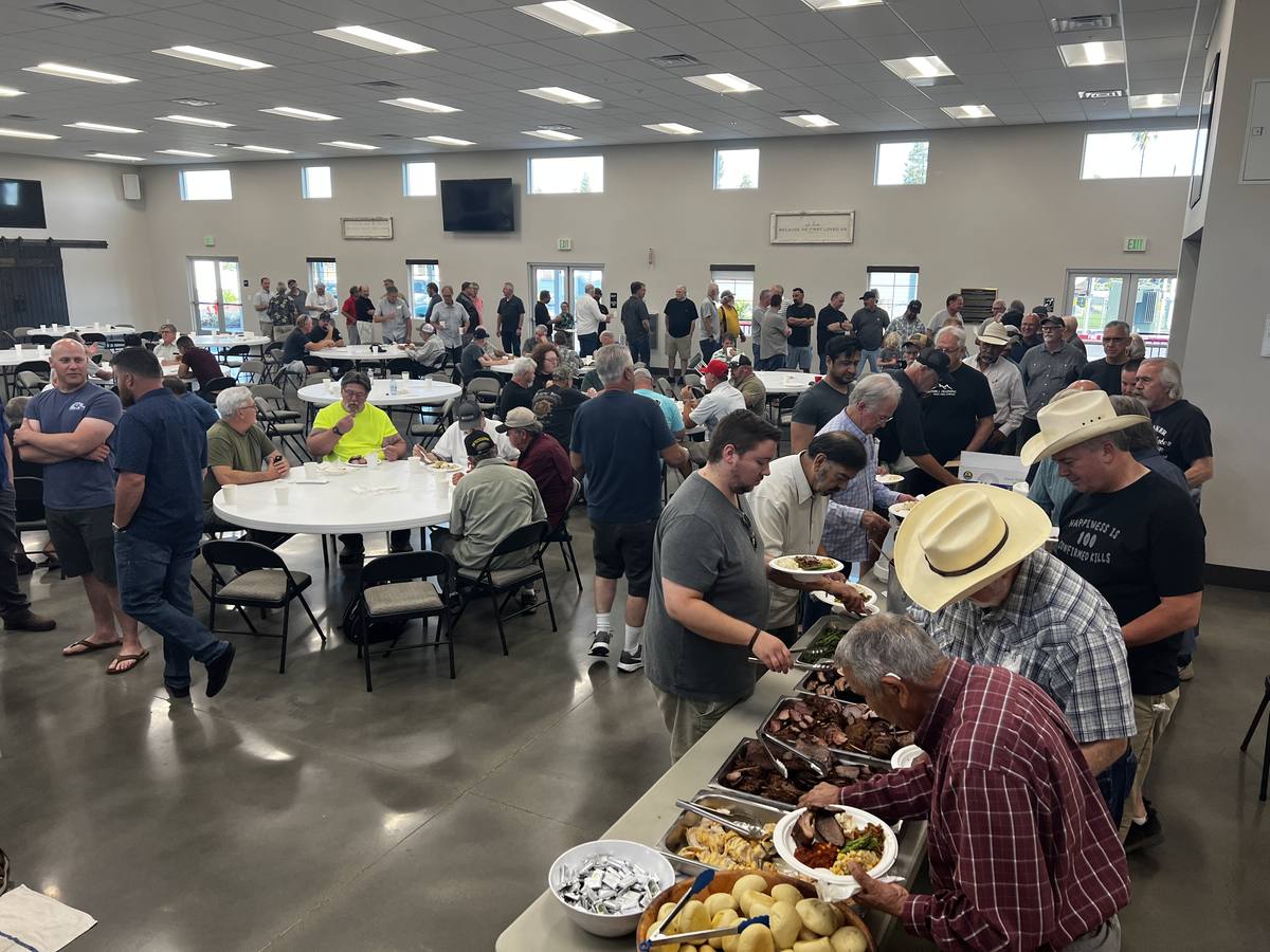 Men gathered around tables for a barbecue in The Barn at New Hope in Clovis