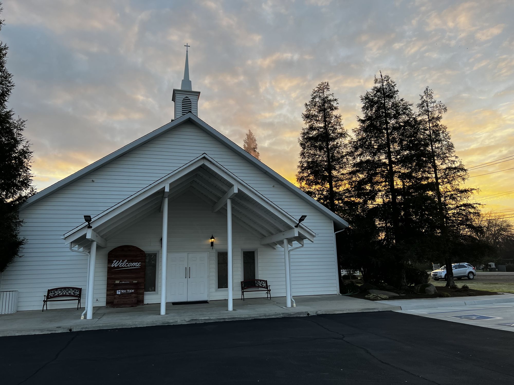 The New Hope sanctuary entrance at sunrise, with its Welcome sign and benches beside the doors