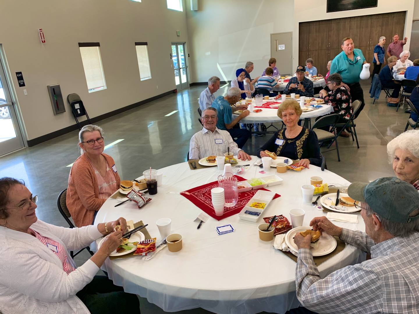 Senior adults of New Hope smiling around a table at the monthly Senior Lunch in Clovis