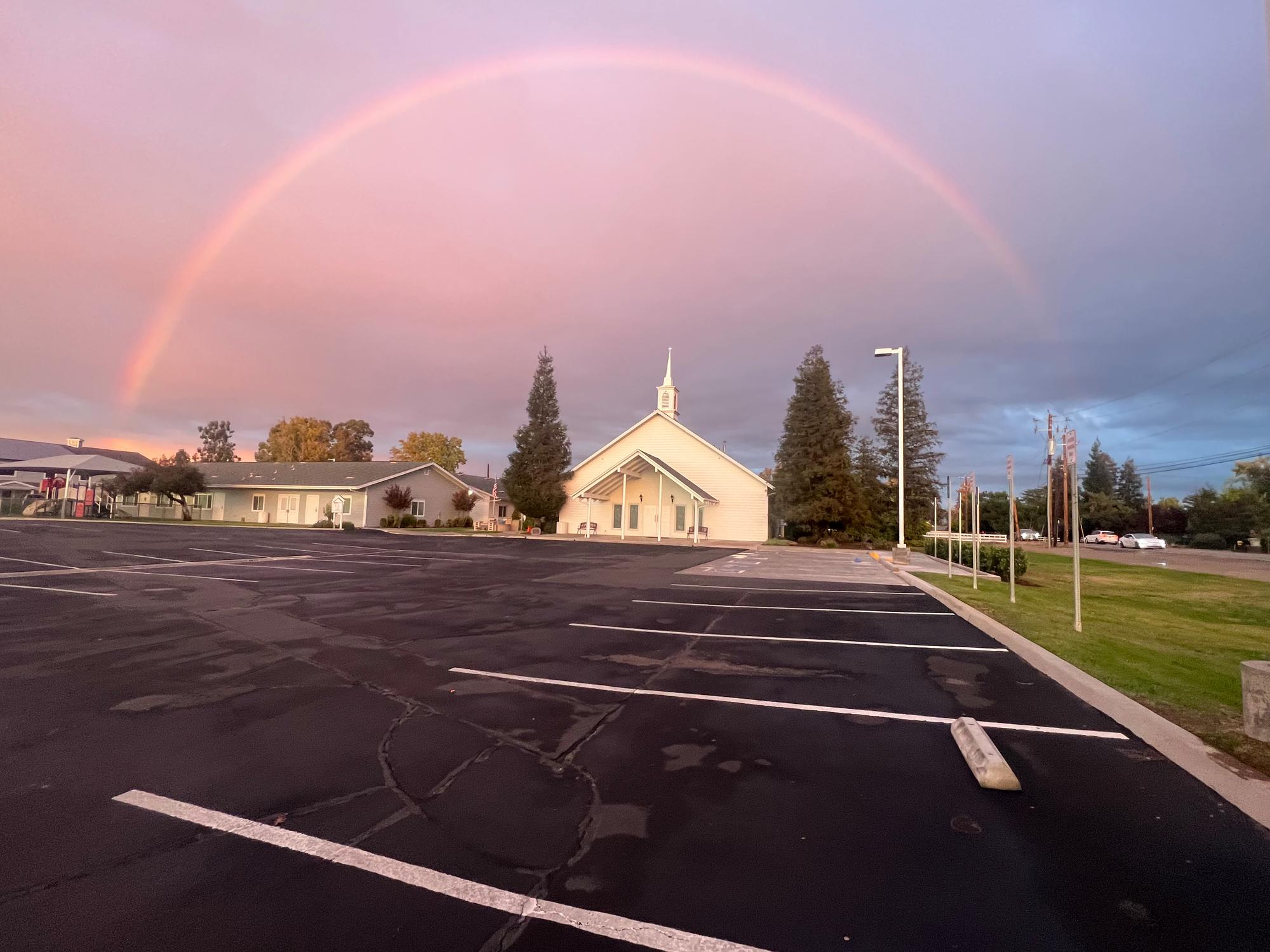 A rainbow over the New Hope church building and parking lot in Clovis