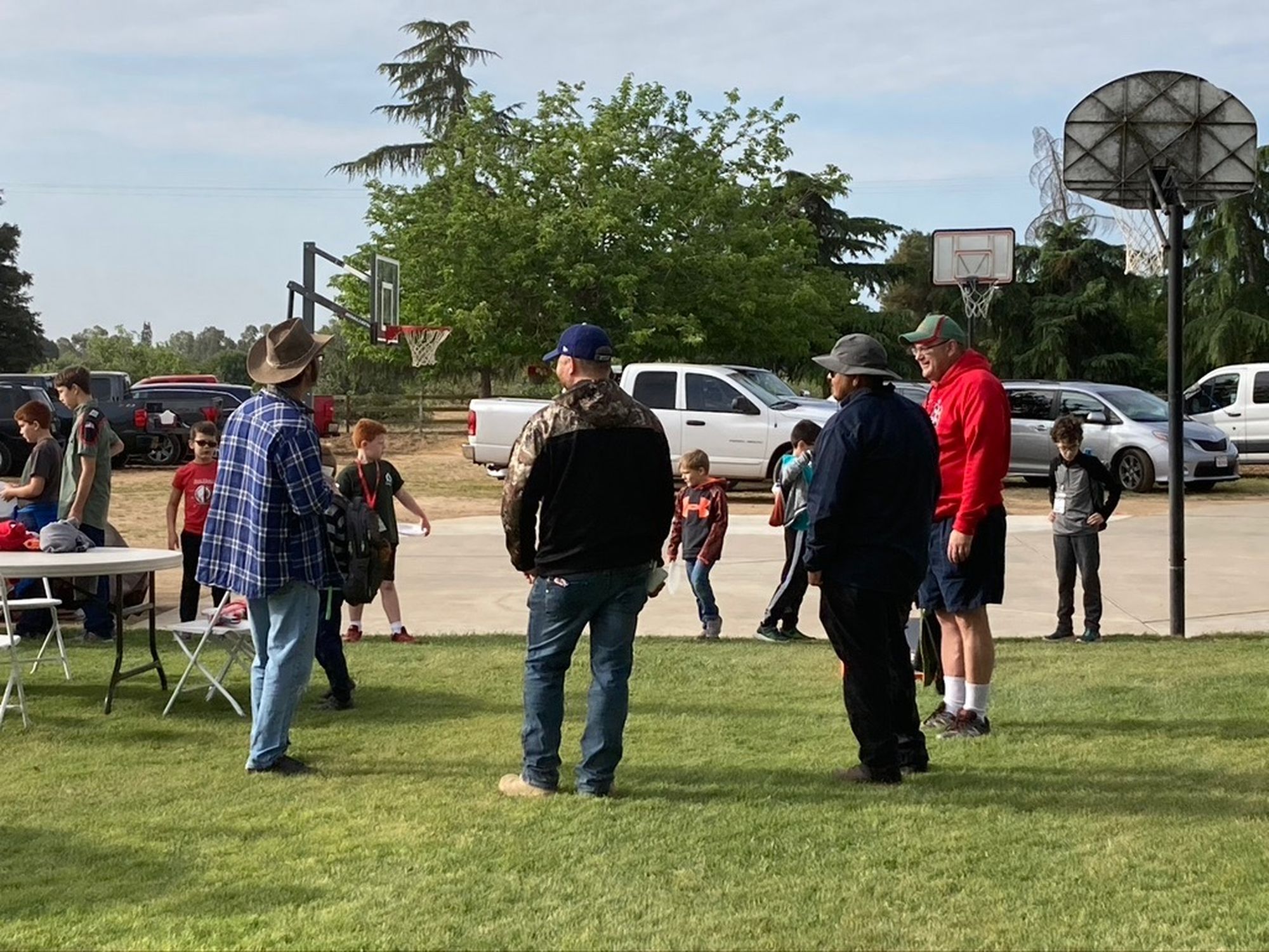 Trail Life dads and boys gathered on the field after an outdoor troop activity