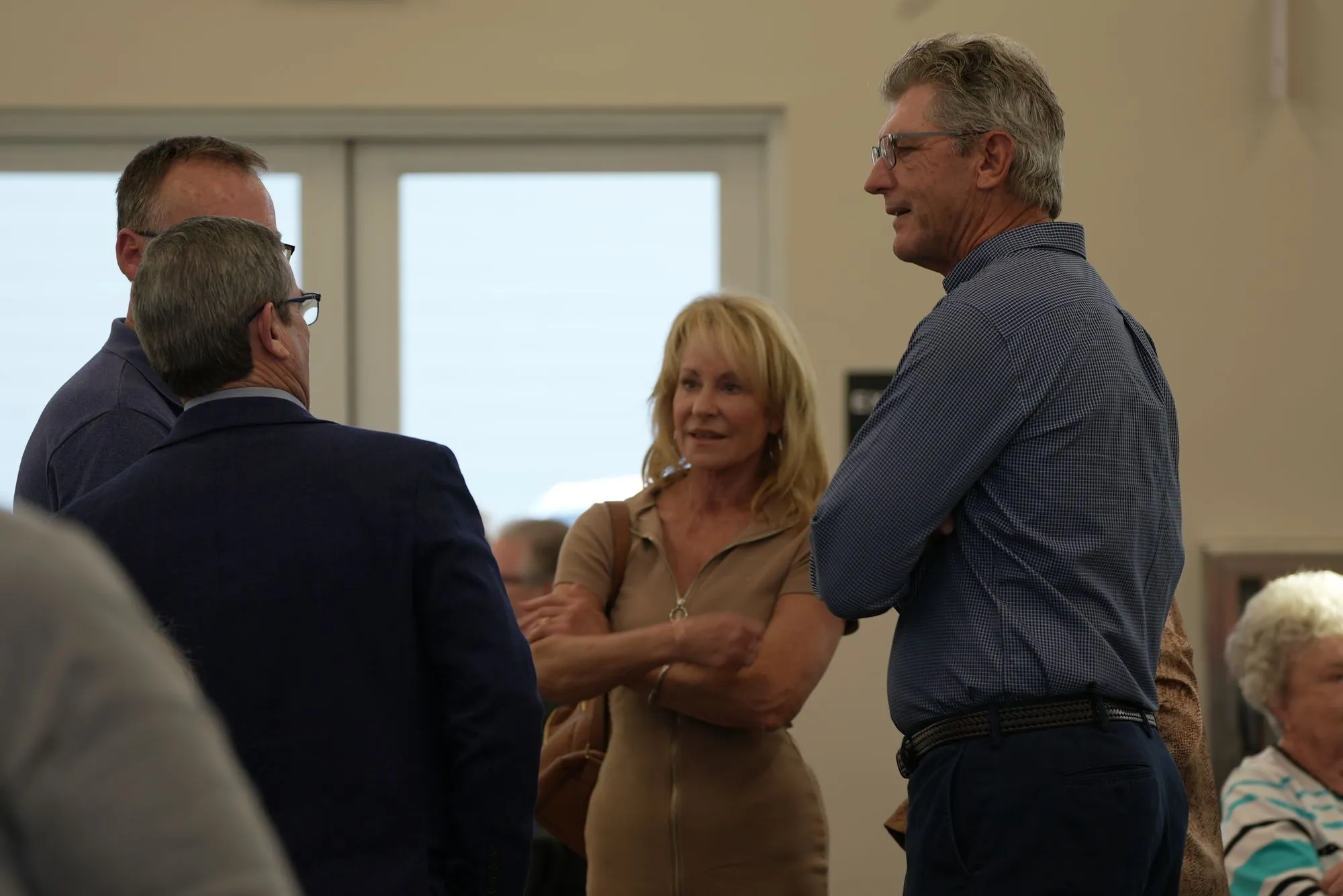Four members of New Hope standing and talking together in a large hall at the church