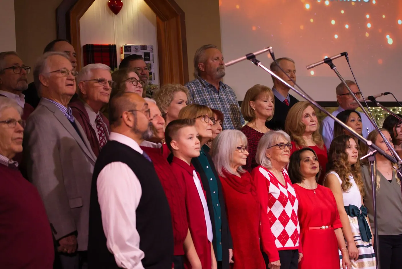 The New Hope Christmas choir standing in rows, many in red, with a boy and a girl among the adults near the front