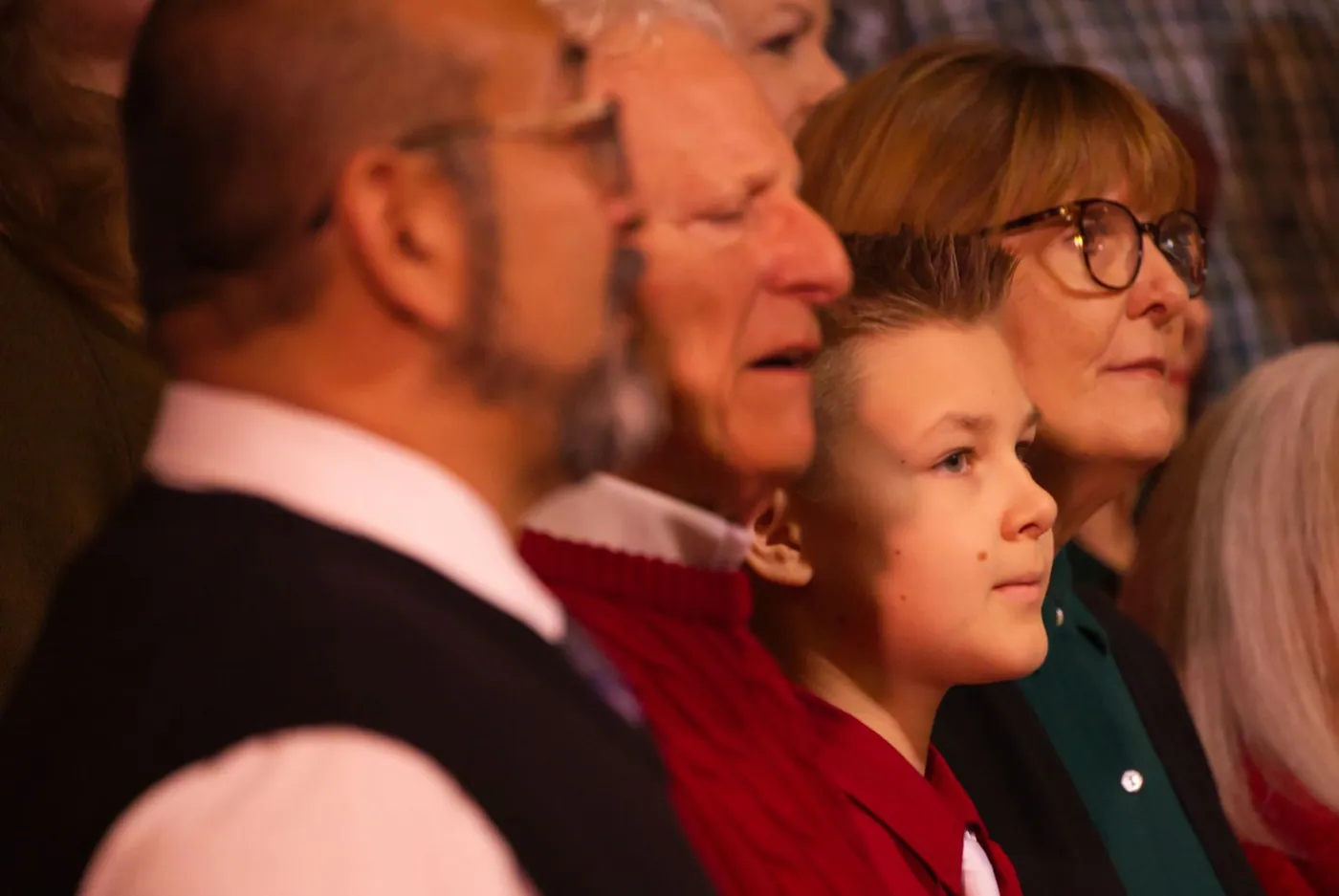 Singers in the New Hope Christmas choir, a boy in red standing between an older man and a woman in glasses