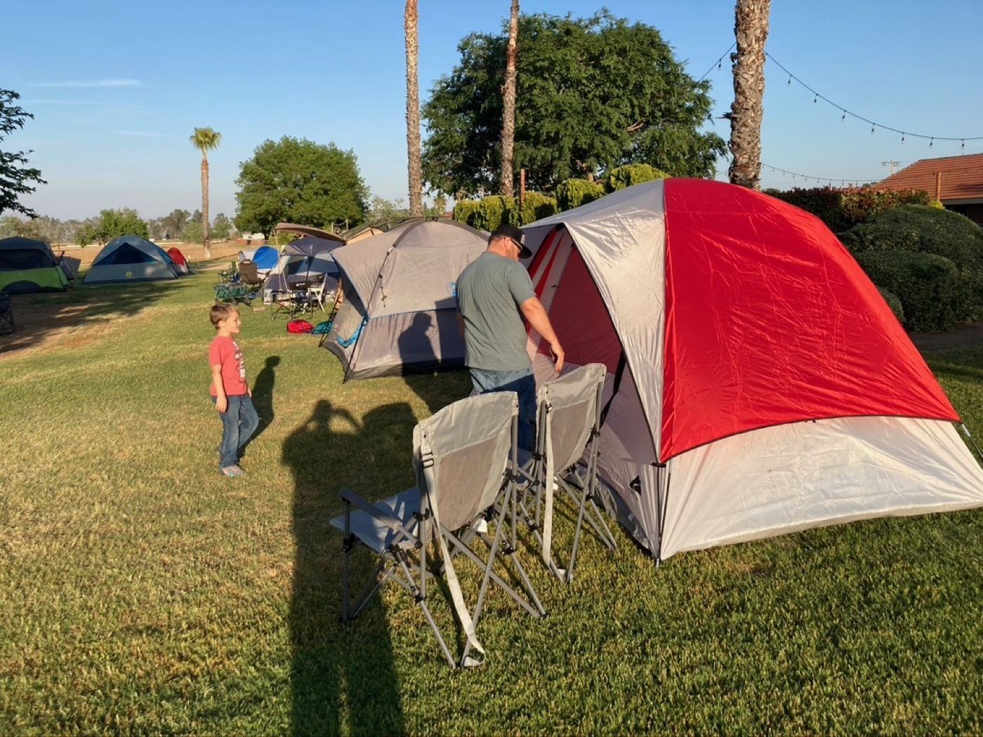 A Trail Life leader and a young Trailman pitching tents at a troop campout