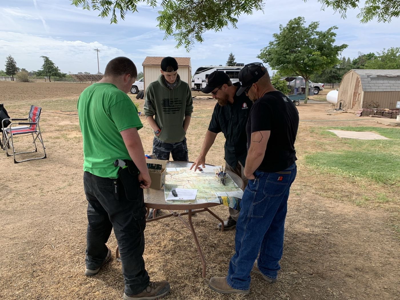Two Trail Life leaders teaching older Trailmen to read a topographic map and compass