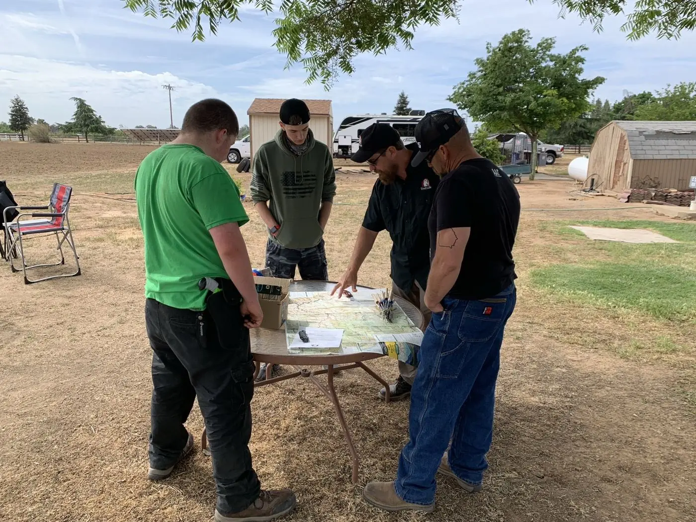 Two Trail Life leaders teaching older Trailmen to read a topographic map and compass