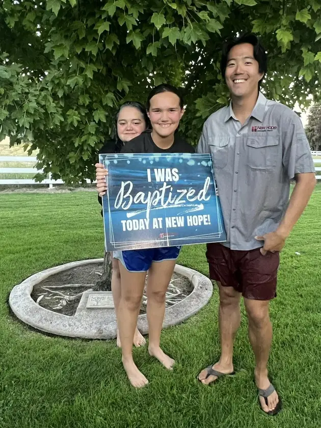 Three people hold a sign that reads I was baptized today at New Hope
