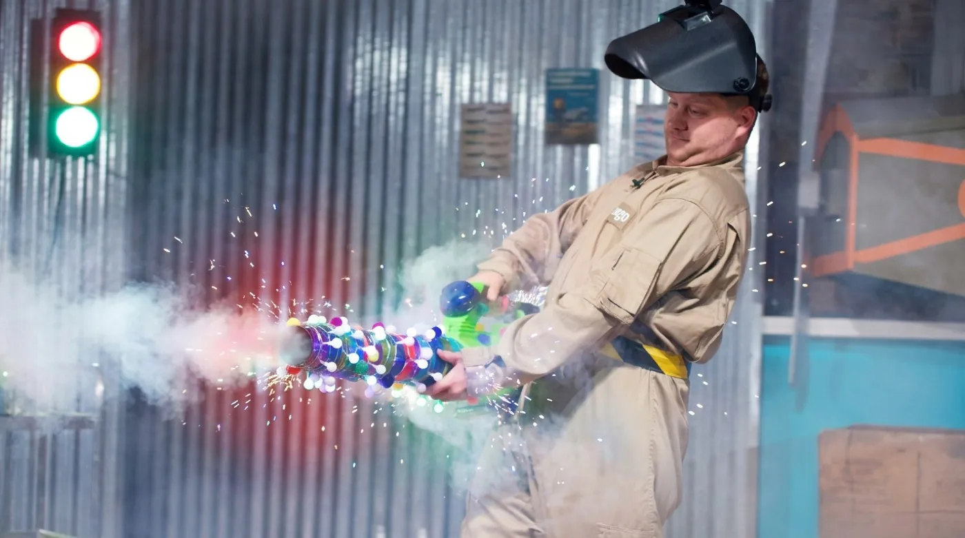 Tango firing the light-up Fog Blaster, smoke and sparks streaming across the stage
