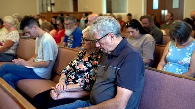 New Hope members praying together during a Sunday morning service