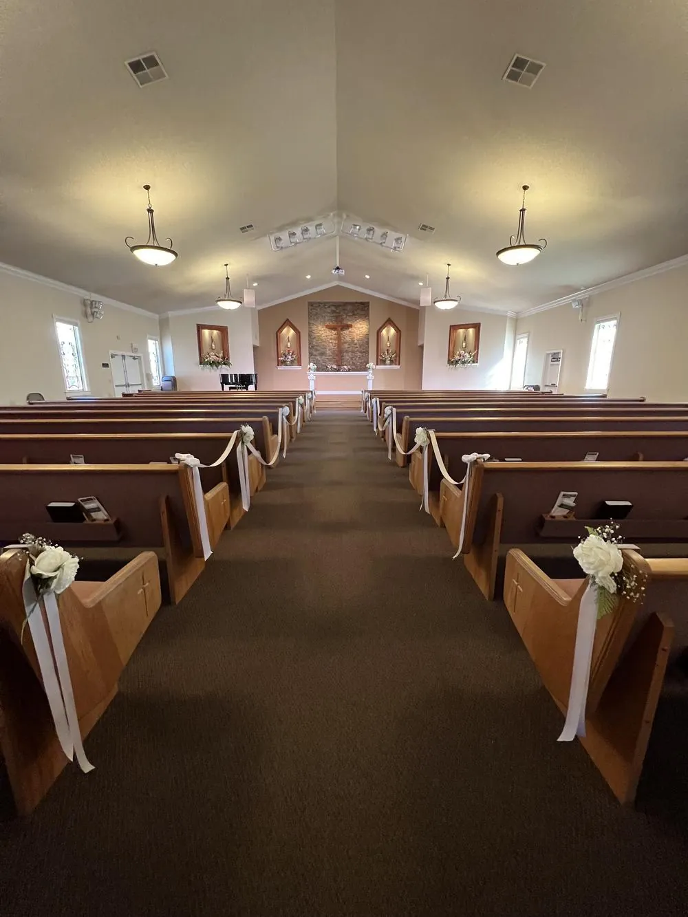 Sanctuary center aisle decorated for a wedding, white bows and flowers on each pew