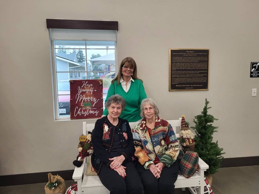Women of New Hope at the Christmas Ornament Exchange with decorated trees and a Merry Christmas sign
