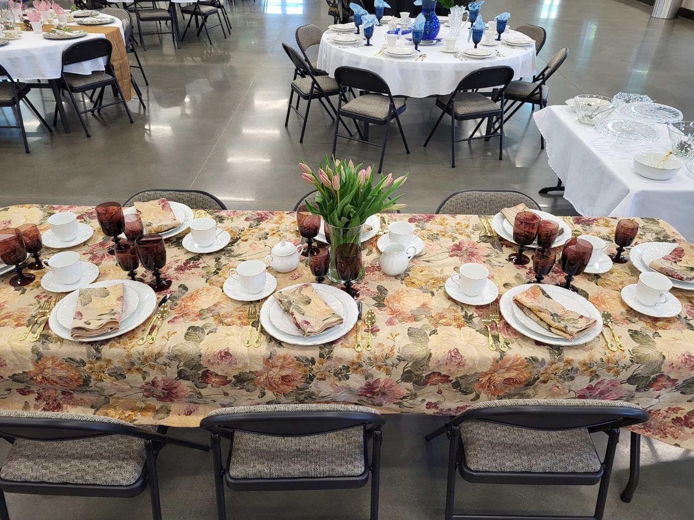 A women's ministry tea table at New Hope set with floral linens, teacups, and tulips