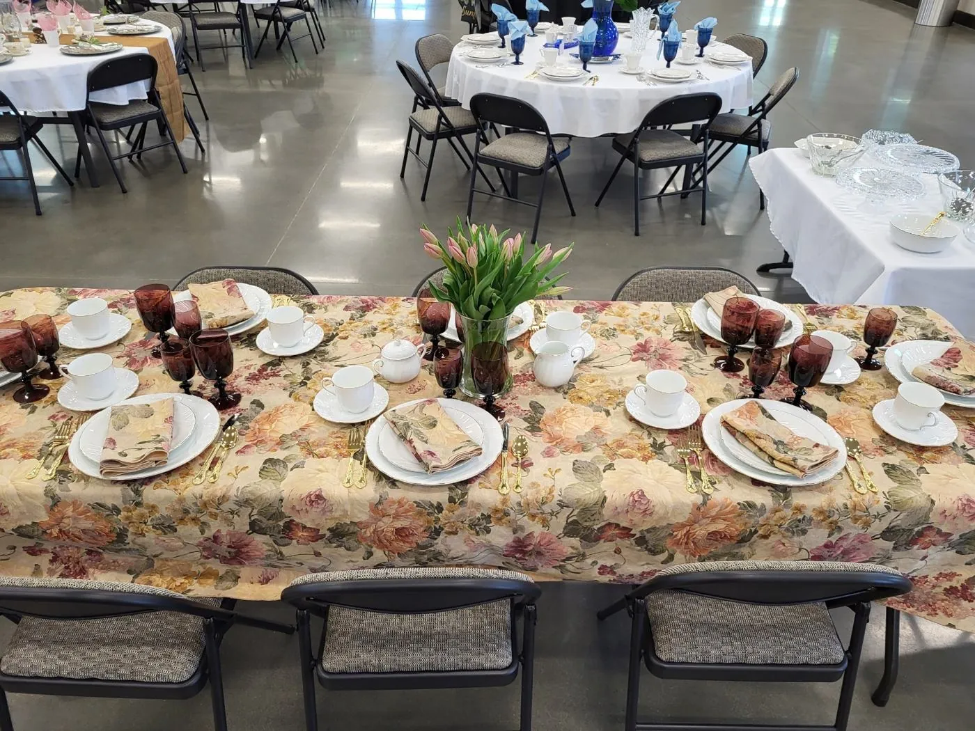 A women's ministry tea table at New Hope set with floral linens, teacups, and tulips